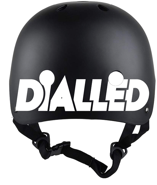 Introducing the Dialled Protection Adjustable Skate / Scooter Helmet in black and white. This stylish helmet features a durable ABS shell, prominently displaying "DIALLED" in bold white lettering across the front. It includes ventilation holes and an adjustable chin strap for enhanced comfort, complemented by a convenient dial adjuster to ensure a perfect fit.