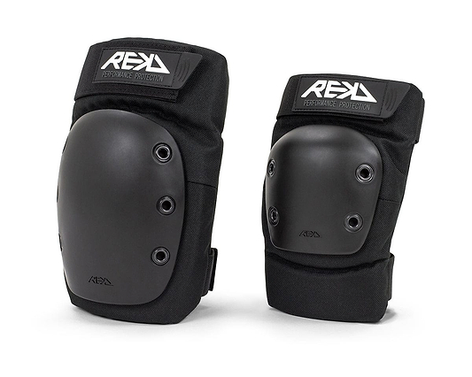 The REKD Ramp Double Skate Protection Pad Set in black features hard protective shells and adjustable straps. With "REKD Performance Protection" branding, these pads provide high-density impact caps for superior protection during action sports. They are presented upright against a white background.
