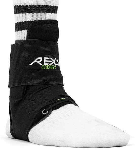 A foot encased in a white sock is comfortably supported by the black REKD Energy Covert Ankle Skate Protection Brace, delivering strong protection for the ankle. The brace is securely fastened with straps, and a black and white striped sock emerges above it, highlighting both style and stability.
