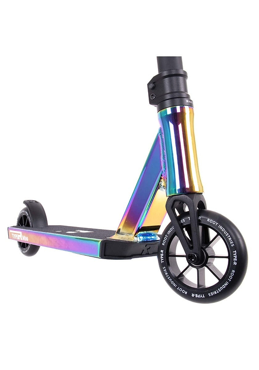 Close-up of the front section of the Root Industries Type R MINI Complete Stunt Scooter - Rocket Fuel Neochrome, highlighting its reflective, multicolor finish. It includes a lightweight aluminium deck and black wheels with white text on the tire rims. The side of the deck prominently features branded text.