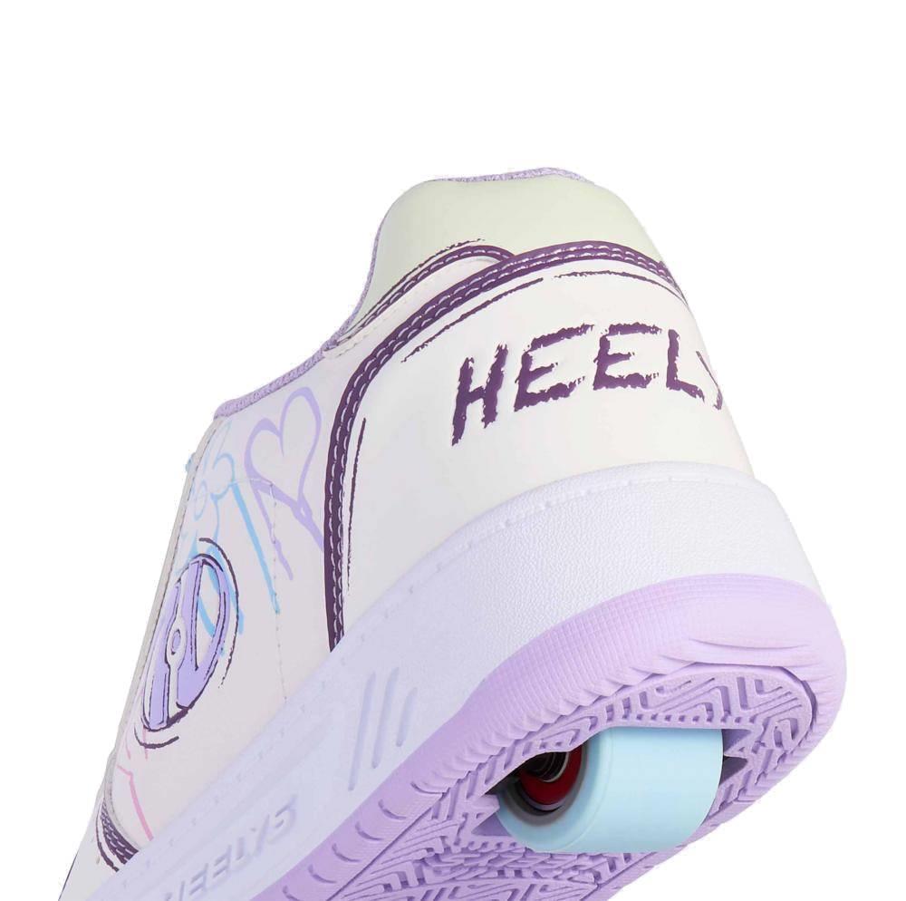 A close-up of Heelys Kama Colour Changing Girls Shoes in white, lilac, and blue shows "HEELYS" on the back and a visible wheel. Light pastel heart and line art accents make these stylish kids' roller shoes from Heelys fun to wear.