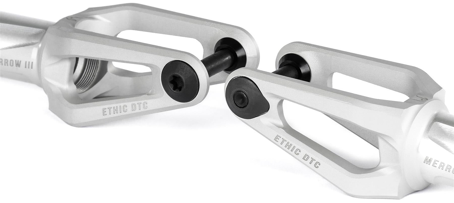 Close-up of two Ethic DTC Merrow V3 8/12STD IHC Stunt Scooter Forks in raw finish, featuring black bolts, "ETHIC DTC" engraving, and a modern lightweight design with cutouts. Brand: Ethic.