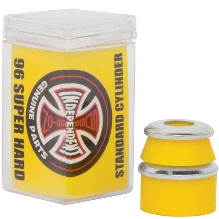A clear plastic container holds Independent Standard Cylinder Yellow Skateboard Bushings, which are made of ultra high rebound urethane and have a 96A hardness rating labeled as "96 Super Hard" and "Standard Cylinder." The container is adorned with the Independent Genuine Parts logo featuring a cross. Two bushings are placed next to the container.