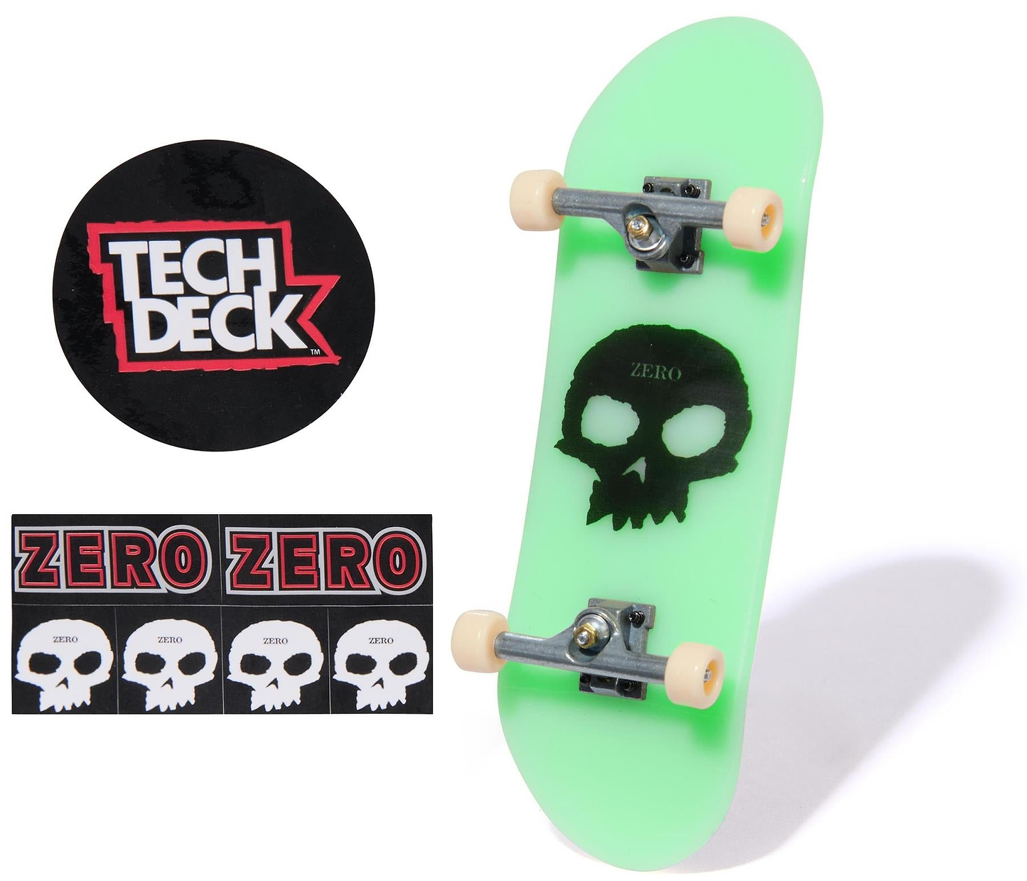 The Tech Deck 96mm M57 Fingerboard - Zero is shown in green with a black skull logo and metal trucks, plus two sticker sheets: one circular "Tech Deck" logo and another with multiple "ZERO" skull logos.