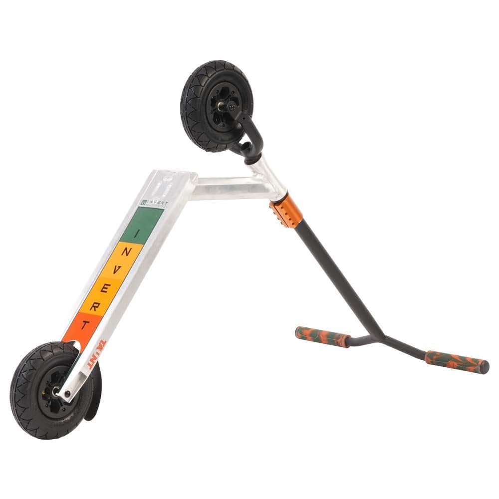 Introducing the Invert Supreme Taunt Dirt Scooter - Raw / Orange / Green, a stylish model from Invert featuring a silver deck boldly displaying "INVERT" in vibrant letters. This scooter is equipped with pneumatic wheels for an impeccably smooth ride and boasts a black handlebar accented with striking orange and green grips. The angled deck perfectly complements its edgy design.