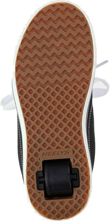 The image shows the sole of a Heelys Pro 25 Boys Shoe in black/white, featuring a brown textured rubber outsole, low-profile wheels near the heel, and "HEELY'S" branding above the wheel.