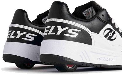 A close-up of Heelys Rezerve Low Boys Shoes in Black/White, featuring the Heelys brand on the heel, retractable wheels in the soles, and ABEC 5 bearings for smooth rolling.