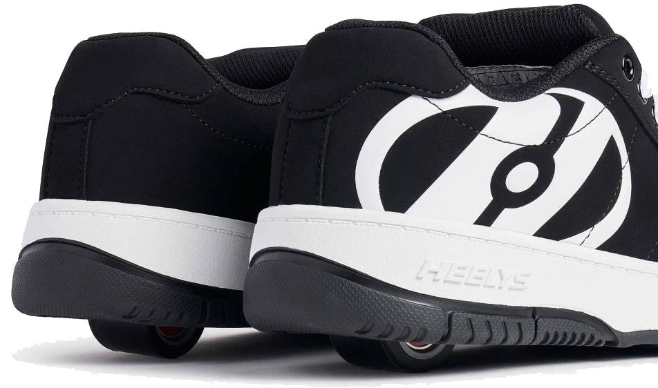 A close-up of the Heelys Kolect Boys Shoes in black with white soles shows the Heelys logo and a wheel with ABEC 5 bearings embedded in each heel outsole.