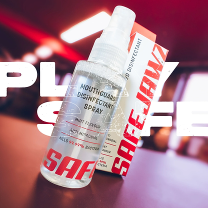 A Safejawz Mouthguard Disinfectant 50ml Spray – Mint, with its box and bold "PLAY SAFE" text, sits on a table; this antibacterial spray kills 99.99% of bacteria for sports hygiene and leaves a refreshing mint flavor.