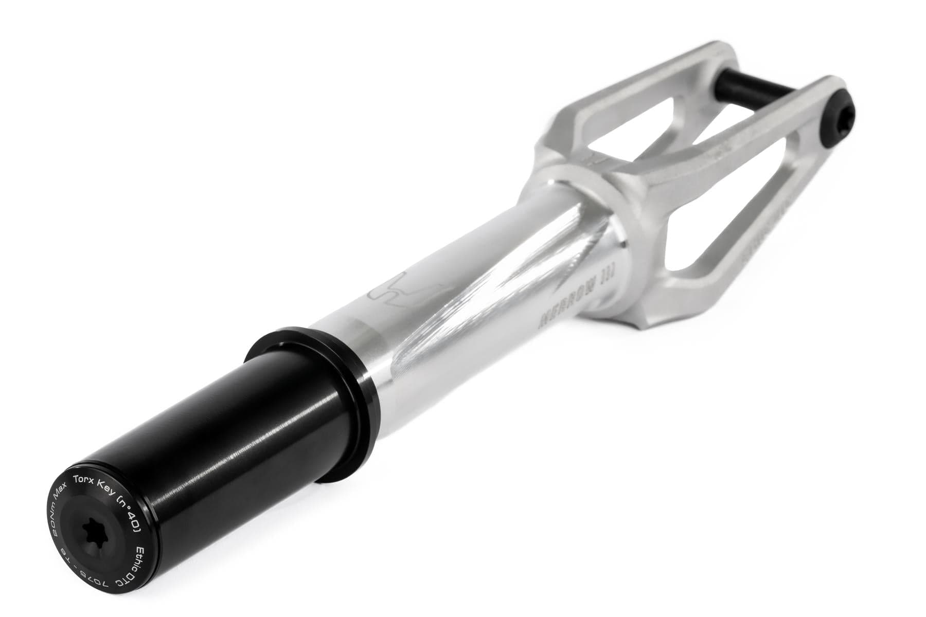The Ethic DTC Merrow V3 IHC Stunt Scooter Fork in raw silver, made by Ethic from 7075 aluminium, features an open angular design, visible engraving, and a black cylindrical axle mount. Photographed on a white background.