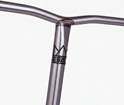 A close-up of the Legacy Chromo Lite Steel Oversized HIC/SCS Stunt Scooter Bars (Raw, 680mm x 610mm) shows a welded chromoly handlebar with a stylized crown and “LEGACY” logo on the vertical bar, set against a plain white background.