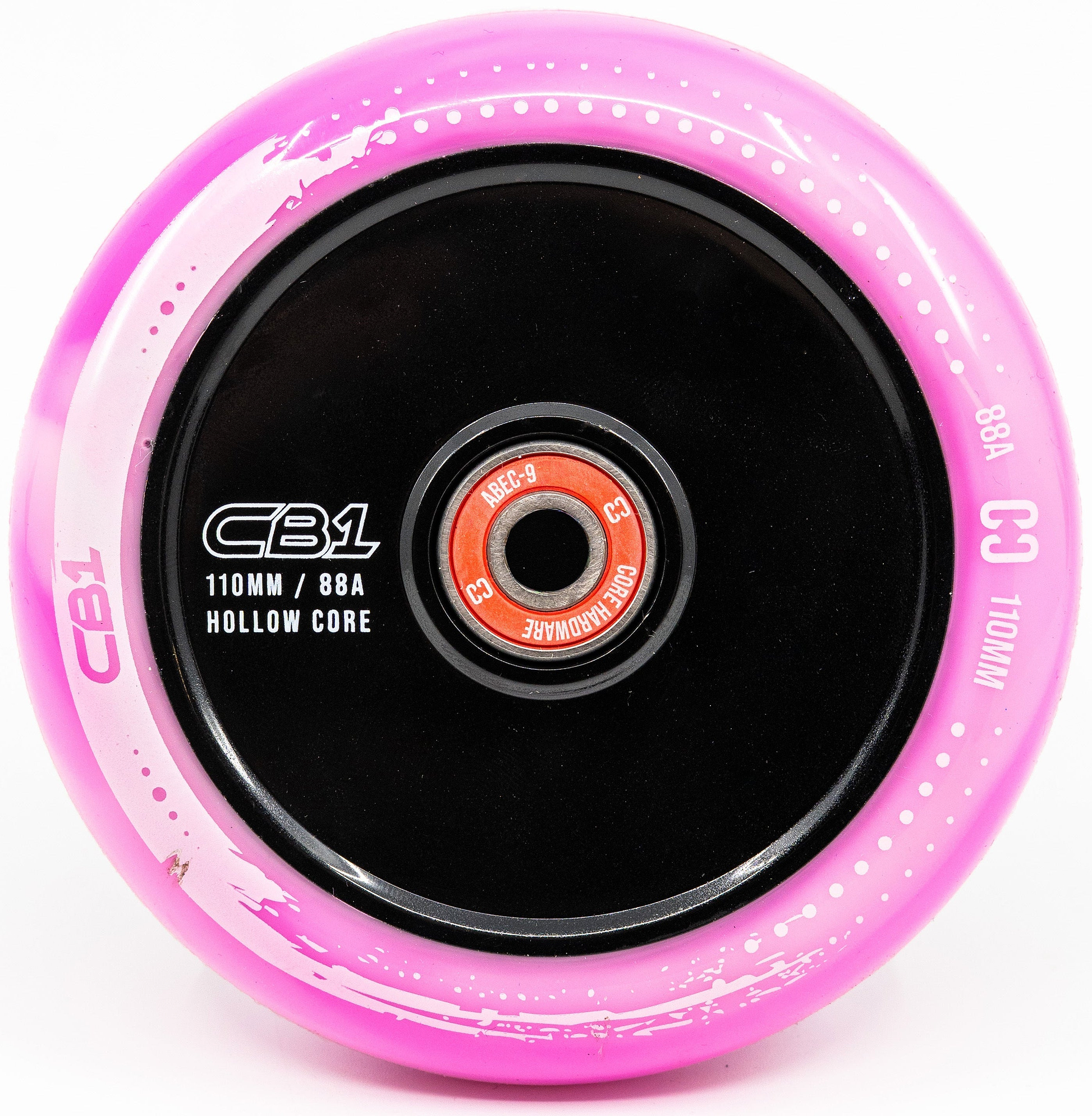 A close-up of the CORE CB1 110mm Nylon Stunt Scooter Wheel in white/pink, featuring a black hollow core and red bearing—perfect for beginners. Text on the wheel includes "CORE," "CB1," and "110mm / 88A Hollow Core.
