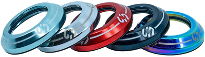 Five metallic CORE Icon Integrated Stunt Scooter Headsets by CORE, in light blue, silver, red, black, and multicolor, are arranged in a row with engraved CORE branding and a sleek curved design.