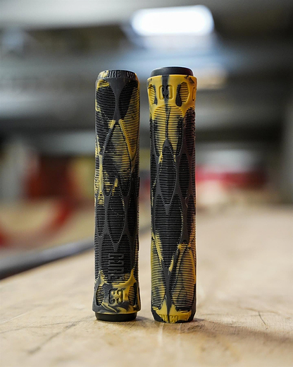 Two CORE Pro Bark Black / Gum Stunt Scooter Grips (170mm) with textured patterns stand upright side by side on a wooden surface, with a blurred indoor background.