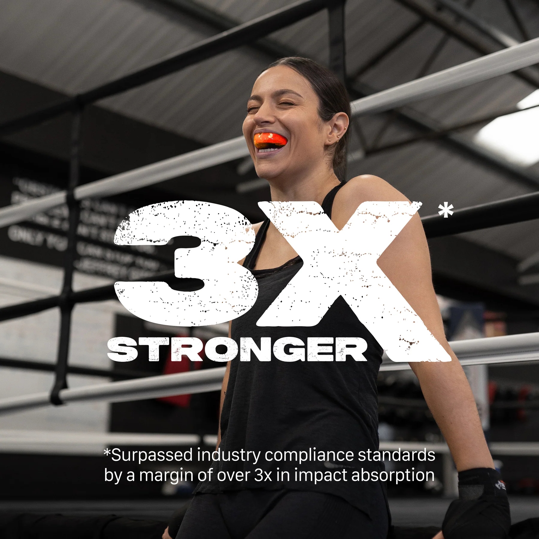 A woman in a boxing ring smiles wearing the Safejawz Intro Series Protection Mouthguard - Fluro Orange. "3x Stronger" highlights its comfortable fit, jaw stability, and over 3 times industry-standard impact absorption by Safejawz.
