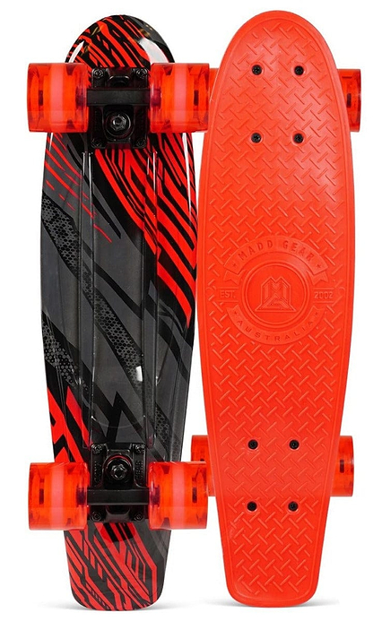 Placed side by side, two Madd Gear MGP G-Retro Racer Complete Cruisers showcase their striking designs. One board displays a textured red top, while the other reveals intricate black and red graphic stripes on the bottom. Both Retro short boards glide smoothly on translucent red wheels equipped with ABEC 9 bearings.