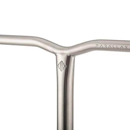 A close-up of the metallic handlebar showcases the minimalist design of the Drone Parallax Titanium HIC Stunt Scooter Y-Bars. "PARALLAX" is engraved on one side, while a geometric logo embellishes the intersection of the durable titanium bars, all presented in a sleek, brushed finish.