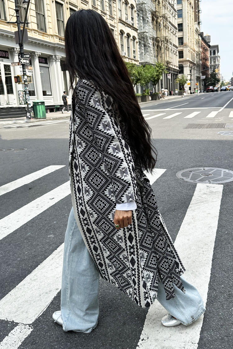 model walking away from camera wearing Black and cream jaquard coatigan