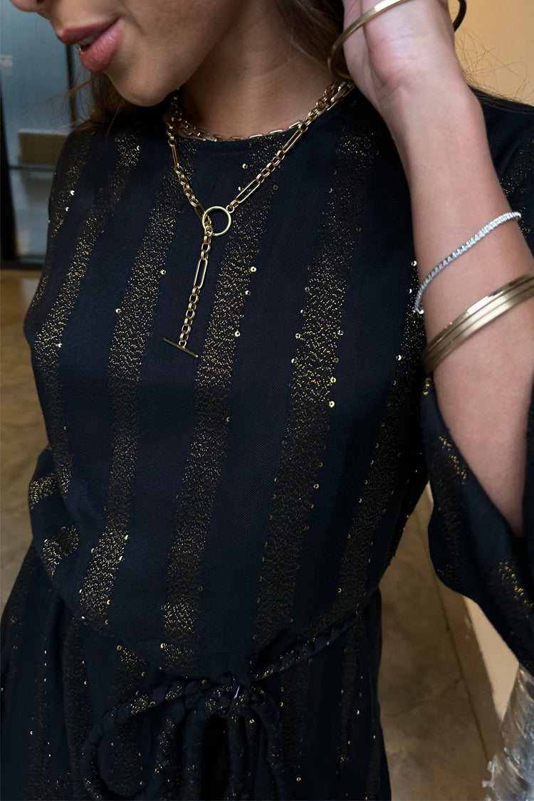 Model wearing Black And Gold Riri Dress