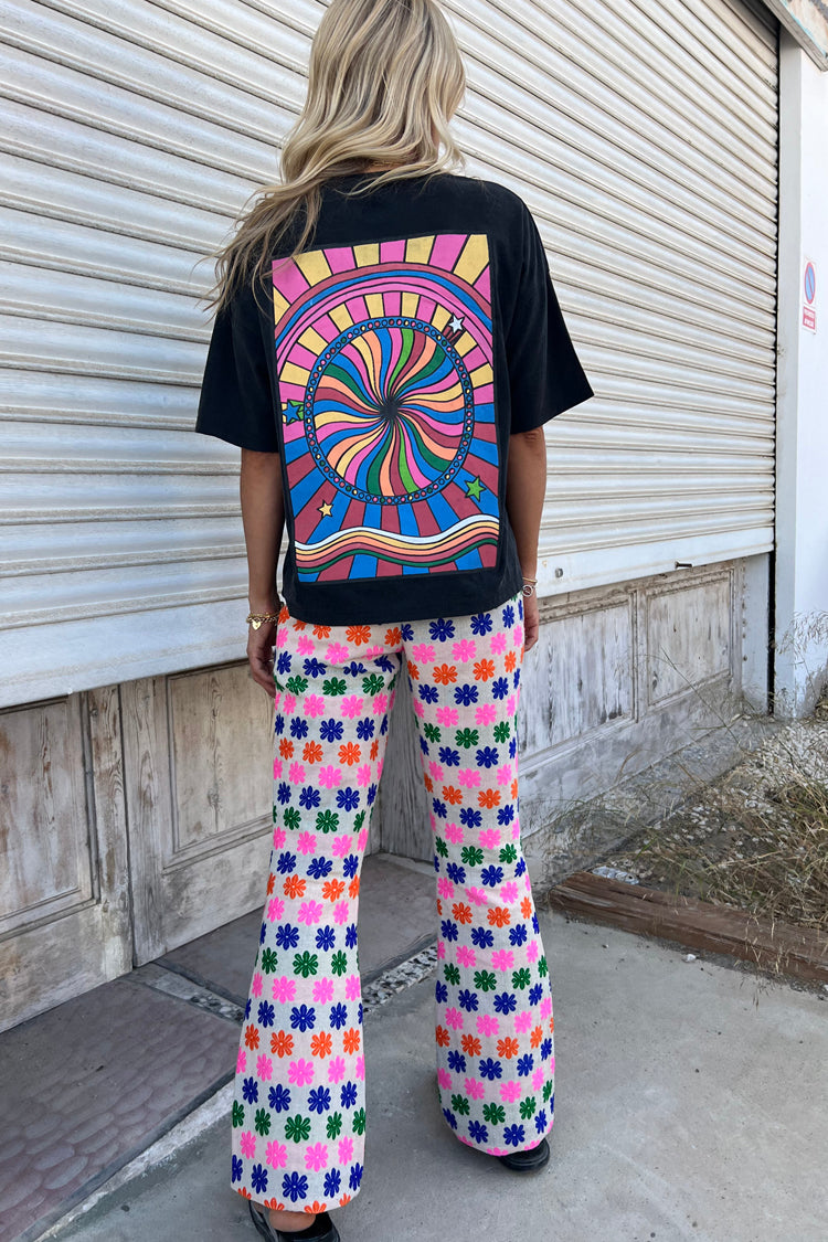 Back of model wearing multi flower trousers and washed black mushroom t-shirt