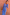 Thumbnail for Model wearing the Blue Eye Mesh Dress Petite, a stretch mesh maxi with eye and heart motifs, against a terracotta wall.