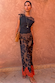 Top in jersey nero e cioccolato con pizzo marrone, abbinato a una gonna floreale su sfondo terracotta.