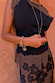 Primo piano del top Black and Chocolate Lace Jersey con bordi in pizzo cioccolato e ciondoli dorati.