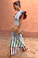 Blue Stripe Alena Midi Dress featuring tiered green and burgundy striped panels, ruffle sleeves and a spotted clutch bag.