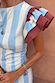 Close up of the Blue Stripe Alena Midi Dress with burgundy ruffled sleeves and gold accessories.