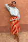 Blue Stripe Batwing Blouse paired with a red striped ruffled skirt against a terracotta wall.