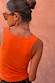 Back view of the coral scoop neck rib tank with embroidered logo detail on the upper back.