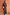 Thumbnail for Model wearing the Chocolate Maeva Skirt with black lace trim and matching blouse against a terracotta wall.