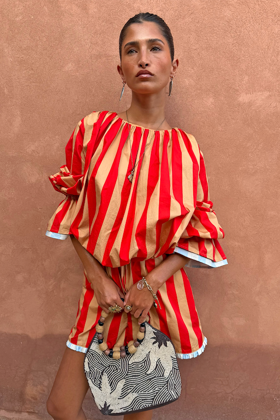 Model wearing the red and camel Tomato Stripe Blouse with voluminous flared sleeves and matching shorts.