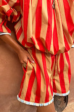 Tomato Stripe Ellie Shorts featuring red and camel stripes, side pockets, and blue striped ruffle trims.