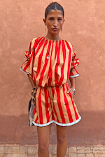 Red and camel Tomato Stripe Ellie Shorts with contrast hem trim styled as a co-ord against a textured wall.