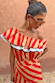 Model wearing the red and camel Tomato Stripe Mini Dress featuring a tiered ruffle neckline with contrast trim.