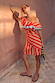 Tomato Stripe Mini Dress with red and camel stripes, styled one-shoulder with a ruffle trim and wrap skirt.