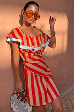 Modella con il mini abito Tomato a righe rosso e cammello, dettaglio volant e occhiali da sole.