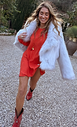 model is wearing the red sundazed mini soho dress with a fur jacket and cowboy boots 