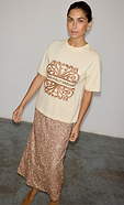 model is wearing the cream logo t-shirt with the gold sequin dorris midi skirt 