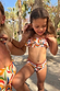 Girl wearing a multicoloured banana print bikini with a ruffled bandeau top and matching bottoms.