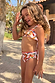 Young girl wearing a multicoloured banana print bikini with a ruffled bandeau top and matching bottoms.