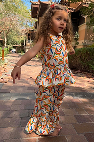 Bambina in completo di cotone con stampa a banane multicolore, top a peplo e pantaloni svasati.