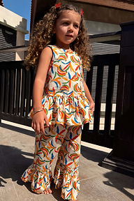 Bambina con completo coordinato in cotone a stampa banane multicolore, top peplo e pantaloni svasati.