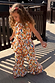 Girl wearing a cream cotton banana print co-ord featuring a peplum top and flared trousers on a sunny deck.