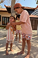 Boy's multi-coloured Banana Print Swim Shorts in recycled polyester worn by children in a vacation setting.