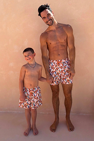 Uomo e bambino con costumi panna coordinati, stampa a banane multicolore e laccetto arancione.