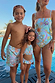 Boy's Starburst Swim Shorts in blue with a colourful sun and star print, shown in a poolside setting.