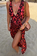 Sarong Black Cherry con stampa di ciliegie rosse e spacco laterale, indossato sulla spiaggia.