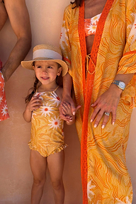 Girl's Yellow Sun Swimsuit with frill details on a young girl wearing a straw hat on vacation.